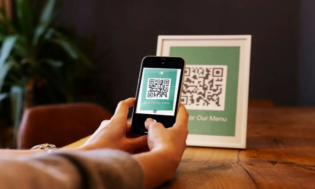 What Are the Advantages of QR Code Ordering for Hotels? 1 Customer using smartphone to scan QR code menu at hotel restaurant table for quick contactless ordering and digital dining experience.
