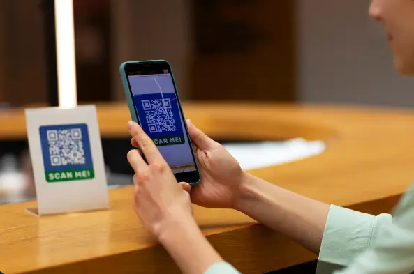 Is QR Code Table Ordering Worth It for Hotel Restaurants? 2 Guest scanning a QR code with a smartphone at a hotel restaurant counter, accessing a digital menu for contactless ordering, faster service, and improved guest convenience.