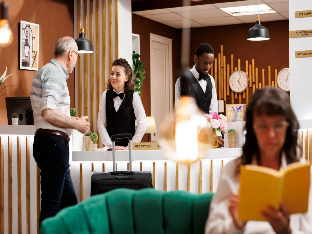 How Can Hotels Reduce Front Desk Wait Times During Peak Check-In Hours? 2 Hotel guest speaking with reception staff during hotel check-in at the front desk